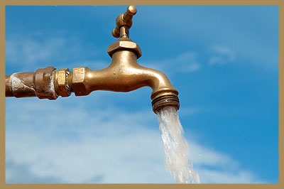 Open water faucet against a blue sky. 