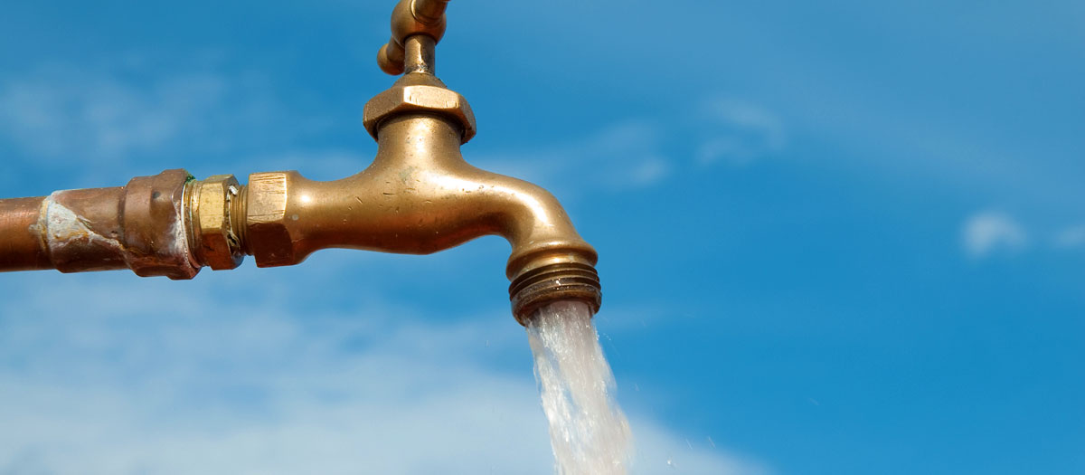 Open water faucet against a blue sky. 